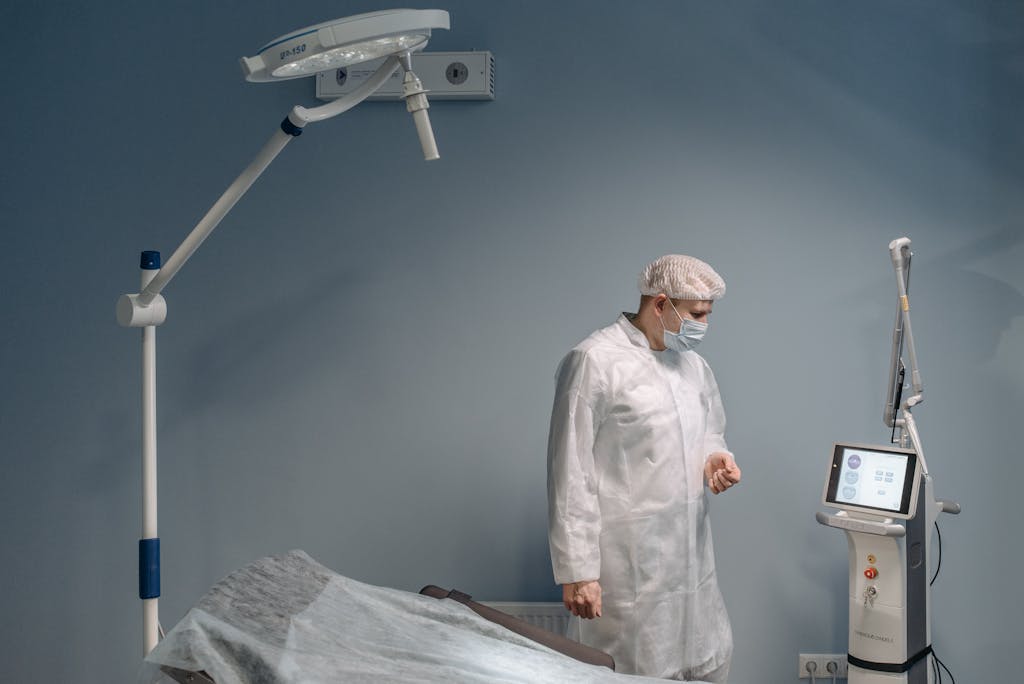 A healthcare professional in protective attire operating advanced medical equipment in a clinic.