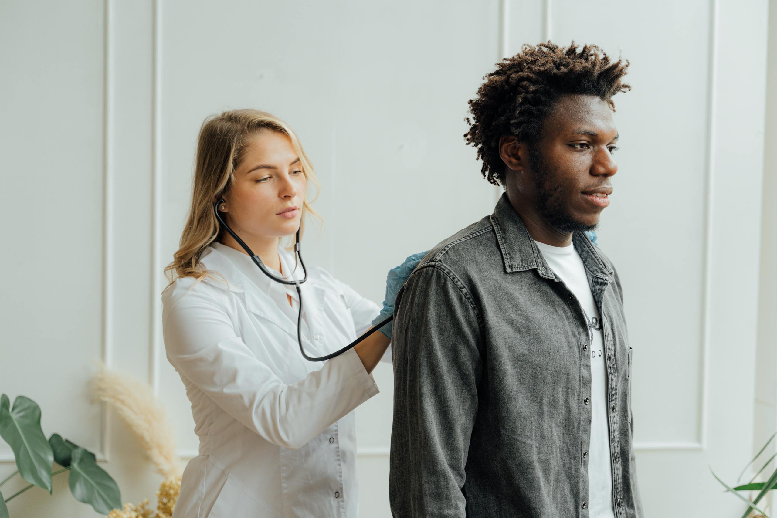 Doctor conducting check-up on patient with stethoscope indoors.